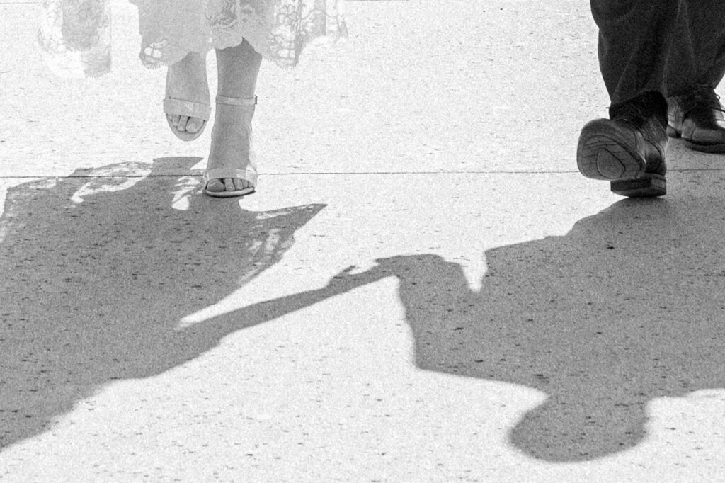 Couple walking together, image is focusing on the shadows in black and white.